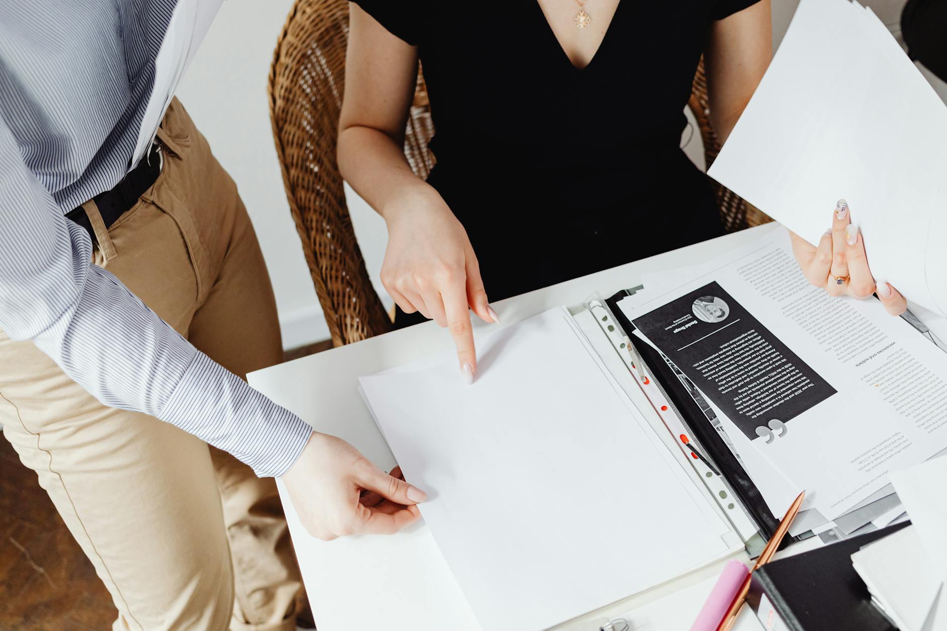 Dos personas revisando documentos sobre una mesa de trabajo